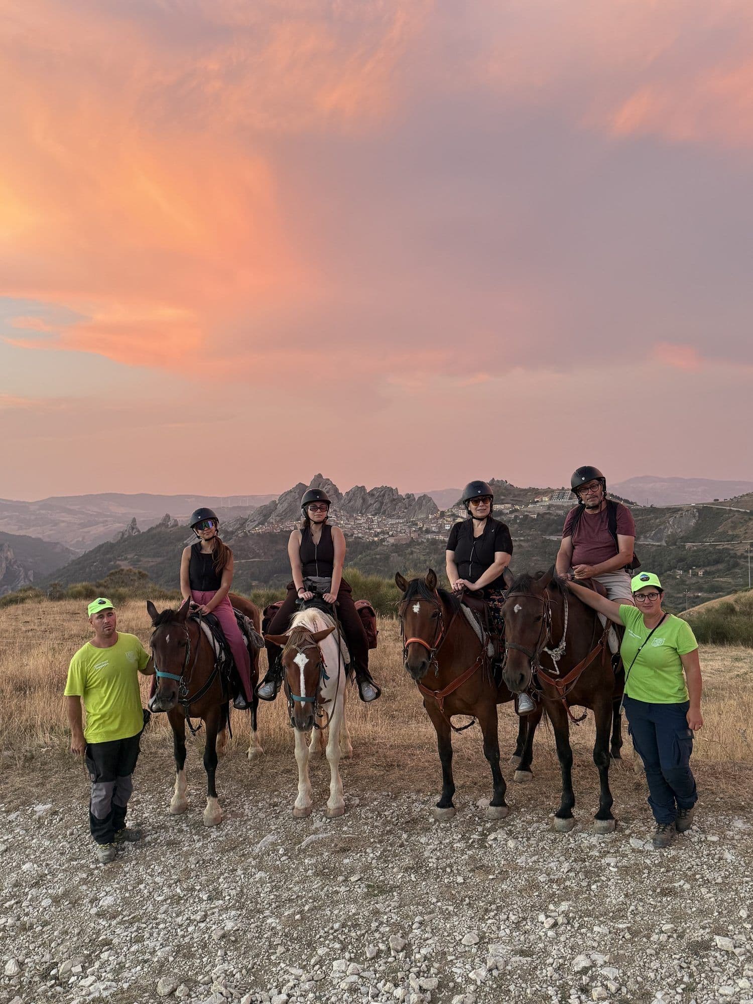 Gruppo di sei cavalieri con le guide al tramonto, guglie di Pietrapertosa e Castelmezzano sullo sfondo