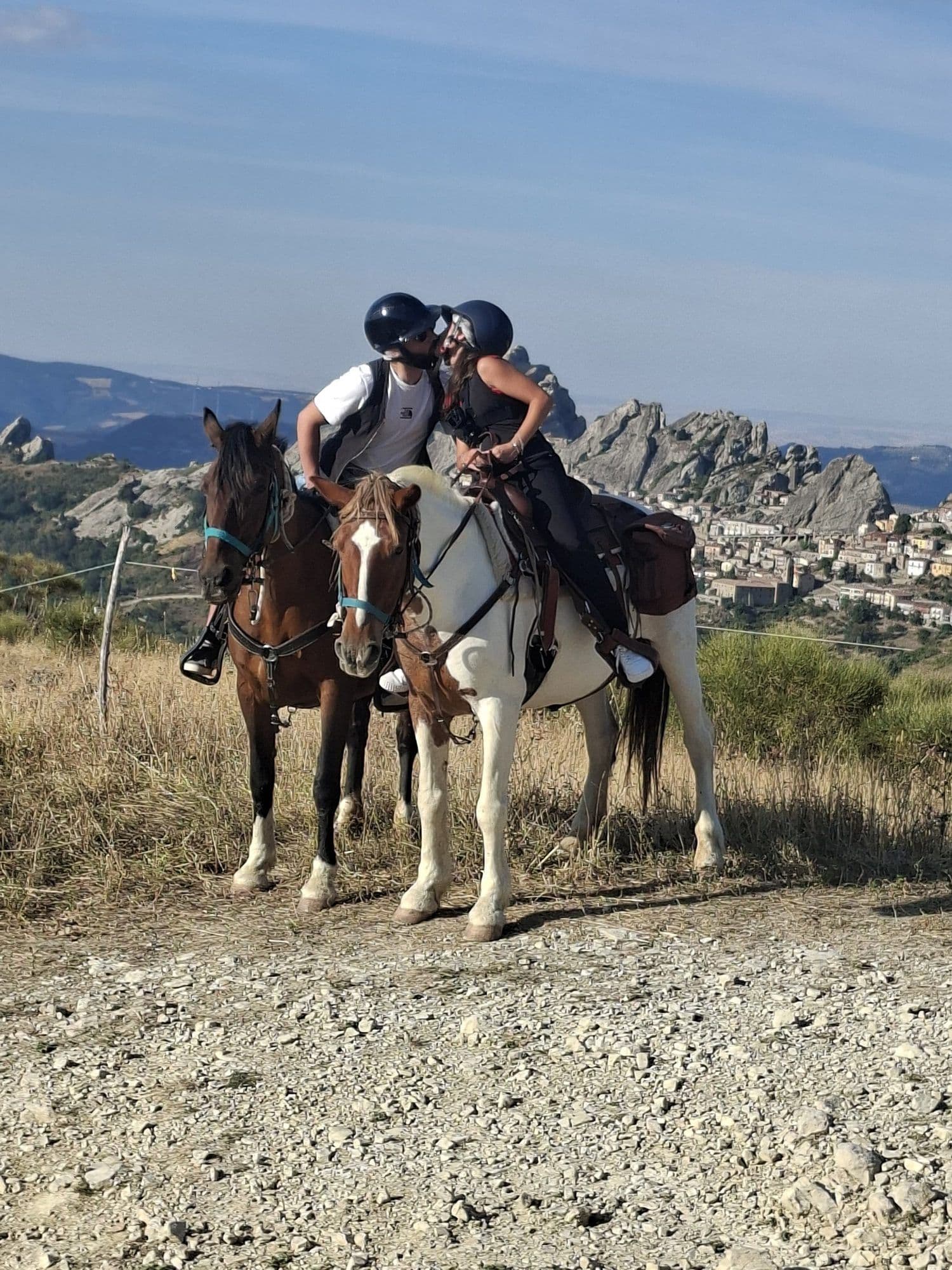 Coppia che si bacia in sella a due cavalli con il borgo di Pietrapertosa sullo sfondo
