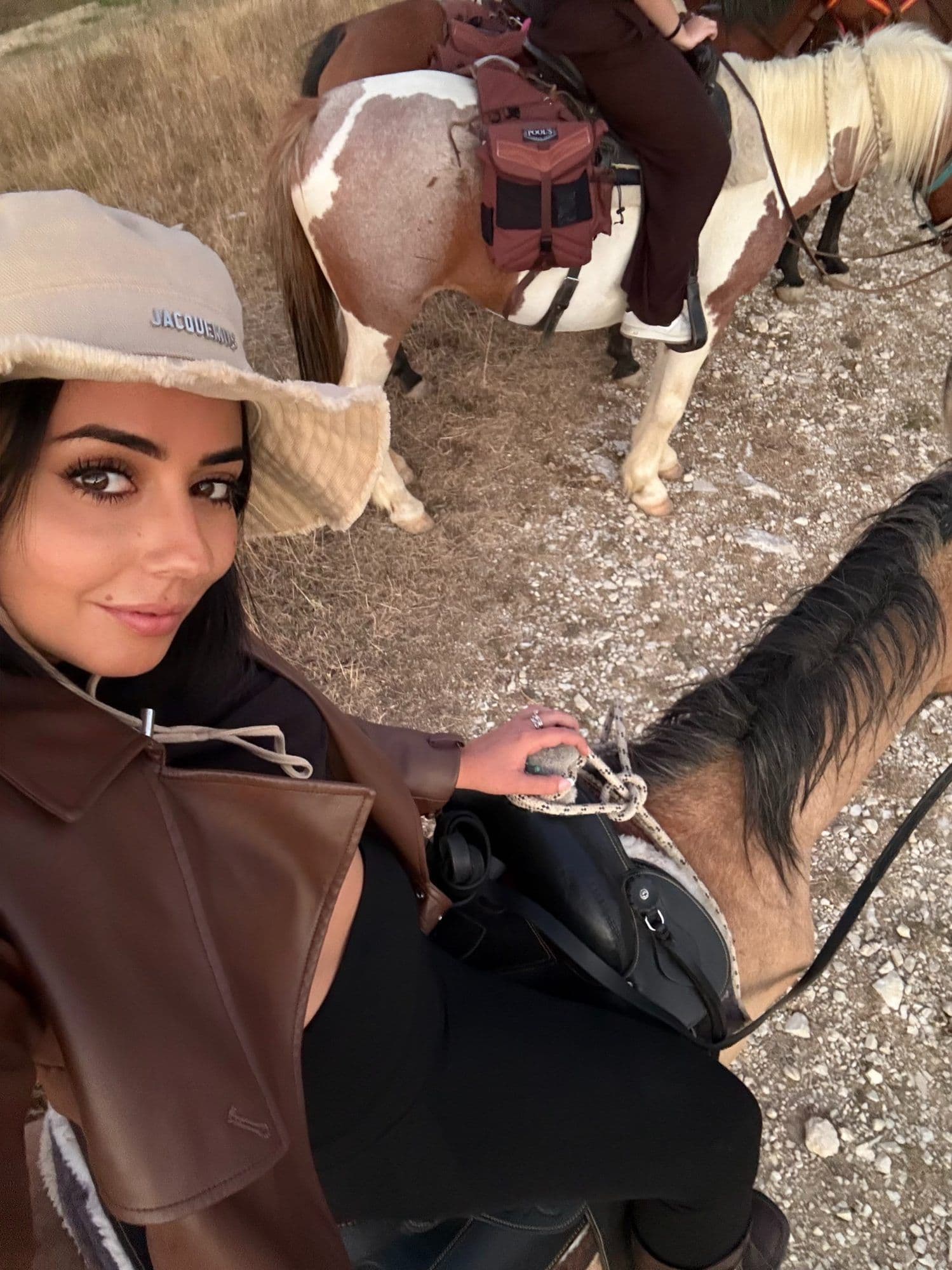 Selfie di una cavaliera accanto a due cavalli pezzati durante una sosta