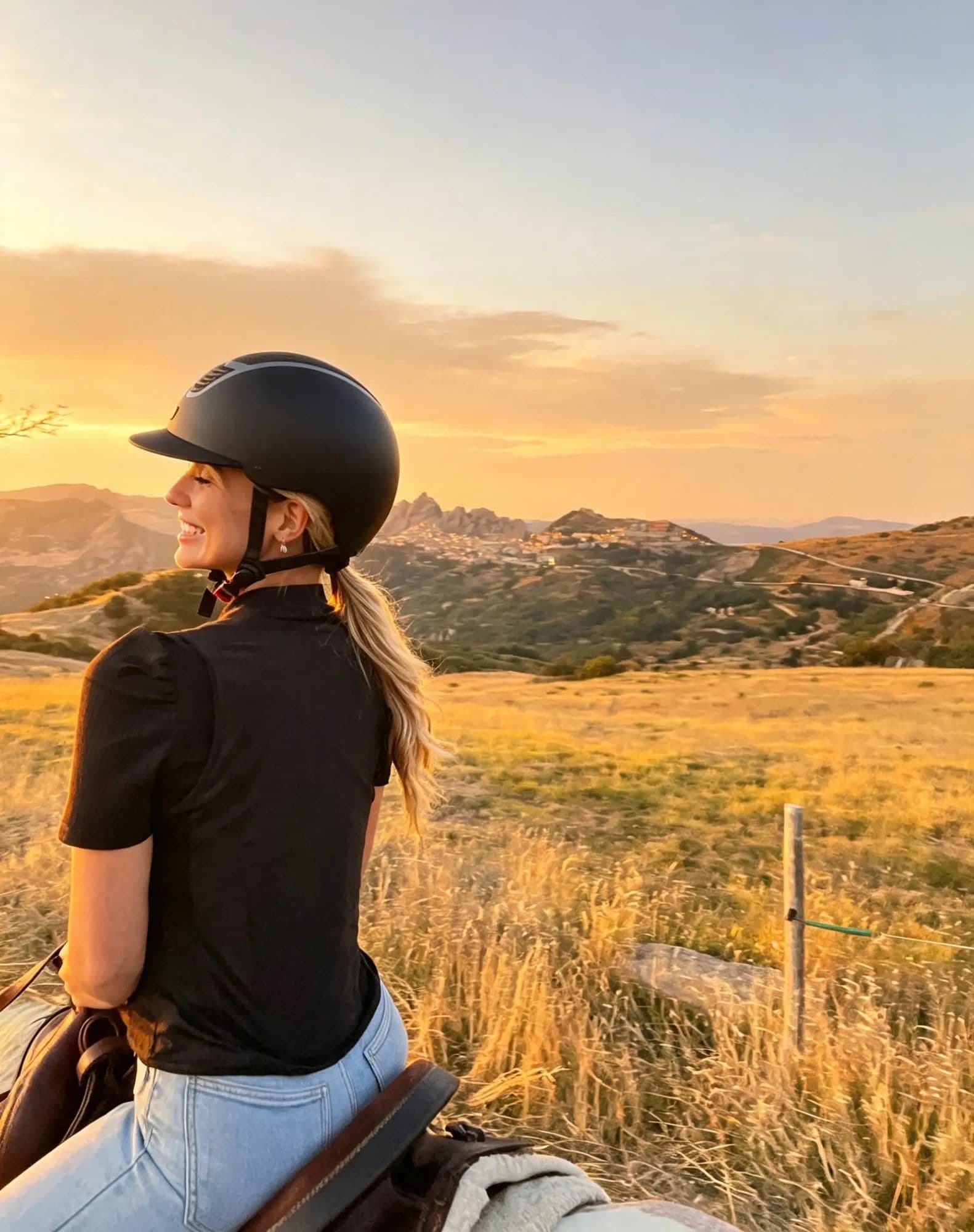 Cavaliera che ammira il panorama dorato del tramonto con il borgo in lontananza